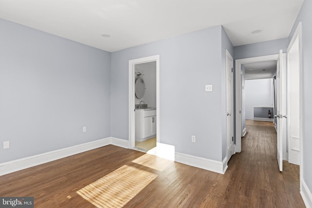 unfurnished bedroom with connected bathroom, dark wood-type flooring, and sink