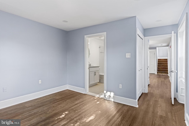 unfurnished bedroom with ensuite bath and dark hardwood / wood-style floors