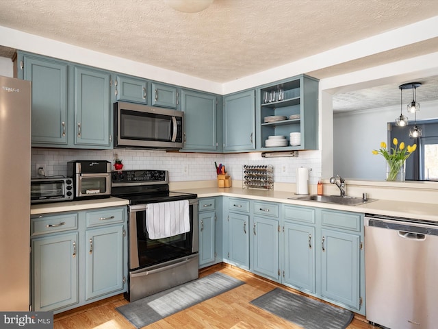 kitchen featuring sink, blue cabinetry, hanging light fixtures, and appliances with stainless steel finishes