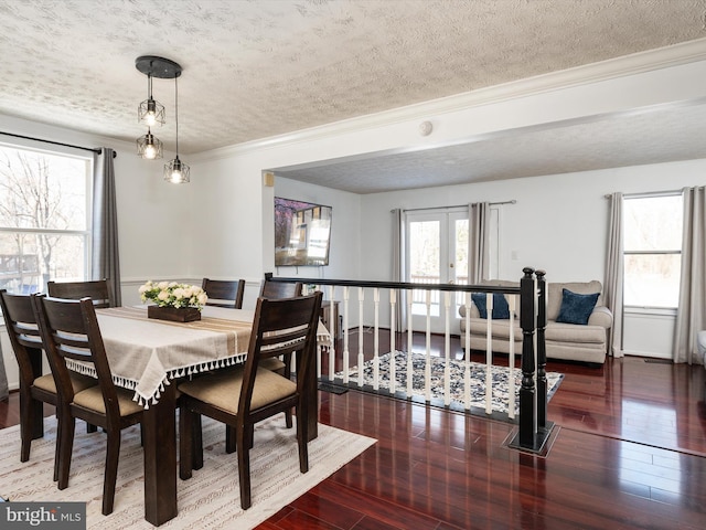 dining room featuring wood-type flooring, a textured ceiling, ornamental molding, and french doors