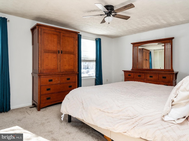 bedroom with light colored carpet, ceiling fan, and a textured ceiling