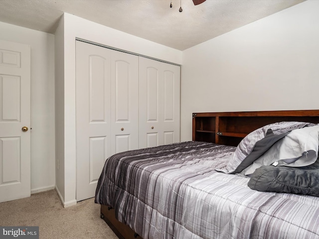 bedroom with light colored carpet, ceiling fan, and a closet