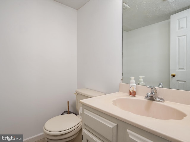 bathroom with toilet, vanity, and a textured ceiling