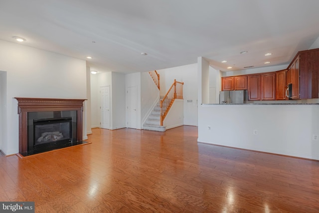 10205 Wincopin Cir Unit 405, Columbia, MD 21044 - unfurnished living room with recessed lighting, light wood-style floors, stairs, and a glass covered fireplace