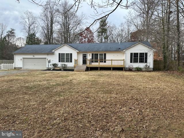 single story home with a garage, a front yard, fence, and a wooden deck