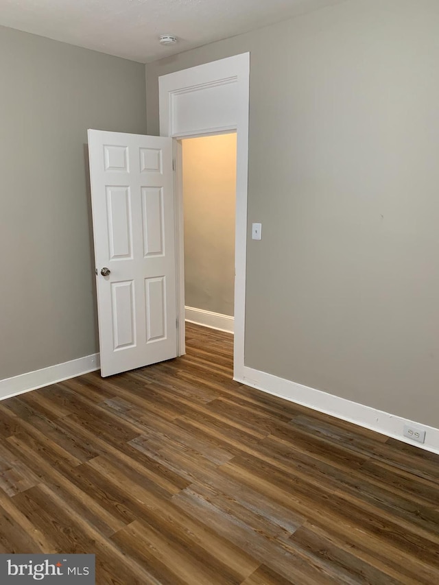 unfurnished room with dark wood-type flooring