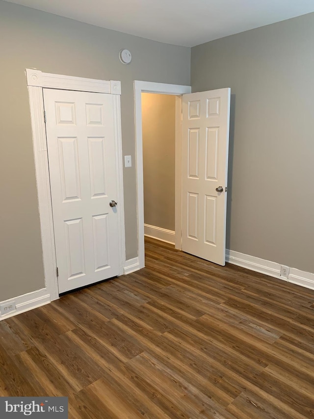 unfurnished bedroom with a closet and dark wood-type flooring