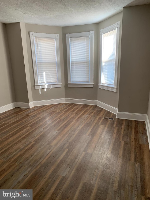 spare room with dark hardwood / wood-style flooring and a textured ceiling