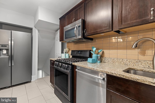 kitchen with decorative backsplash, appliances with stainless steel finishes, light stone countertops, sink, and light tile patterned floors