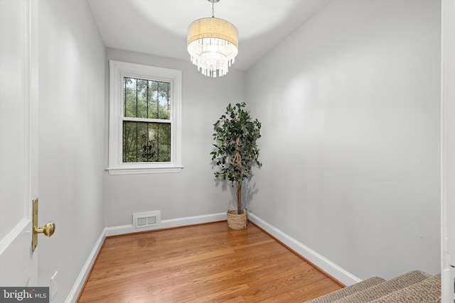 empty room featuring a chandelier and light hardwood / wood-style flooring