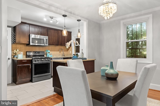 dining space with light hardwood / wood-style floors, crown molding, and a chandelier