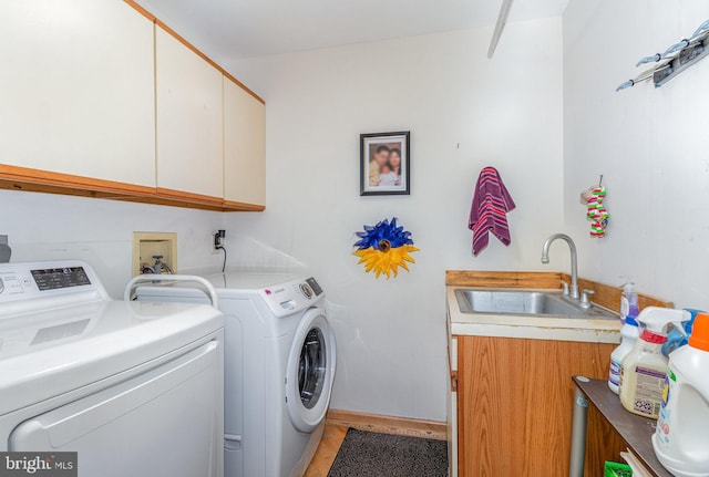 clothes washing area featuring separate washer and dryer, sink, and cabinets