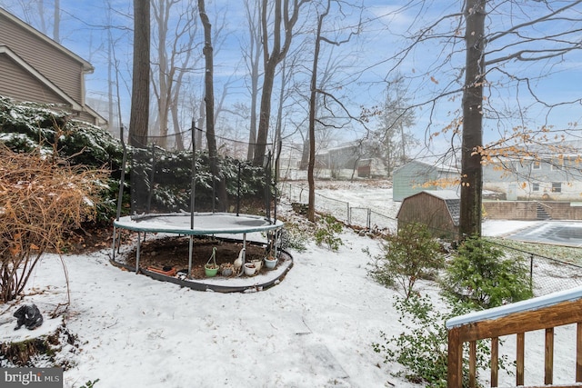 yard layered in snow with a trampoline