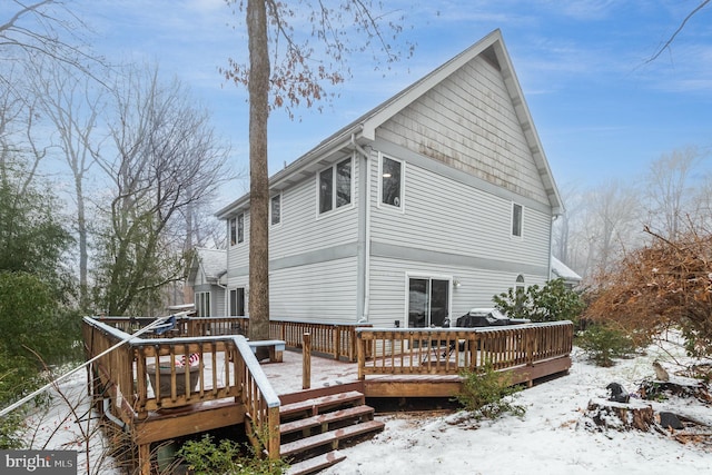 snow covered back of property with a deck