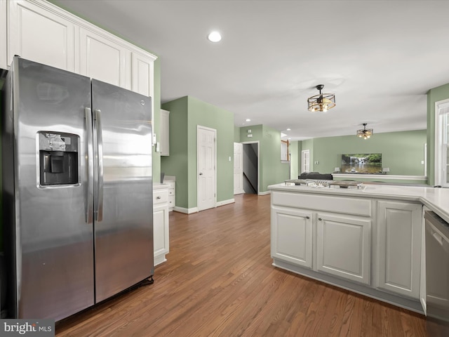 kitchen featuring kitchen peninsula, stainless steel appliances, dark wood-type flooring, and white cabinetry