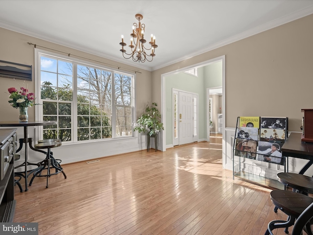 office space featuring ornamental molding, an inviting chandelier, and light hardwood / wood-style floors