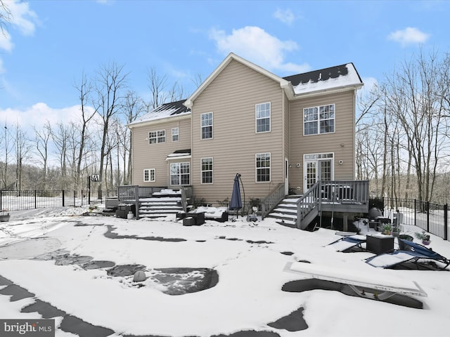 snow covered back of property featuring a wooden deck