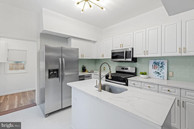 kitchen featuring white cabinets, appliances with stainless steel finishes, tasteful backsplash, and light stone counters