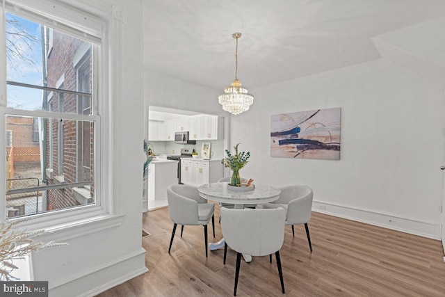 dining space featuring light wood-type flooring and a chandelier