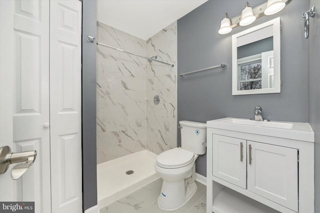 bathroom with a tile shower, vanity, and toilet