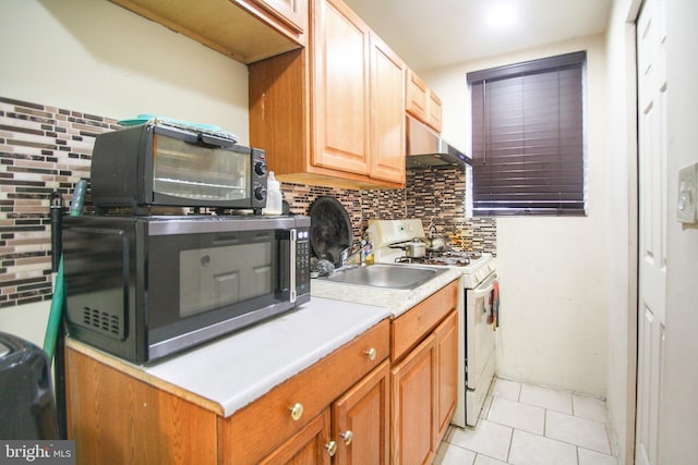 kitchen with appliances with stainless steel finishes, backsplash, and light tile patterned flooring