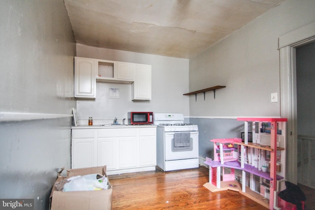 kitchen featuring white range with gas cooktop, sink, white cabinets, and hardwood / wood-style flooring