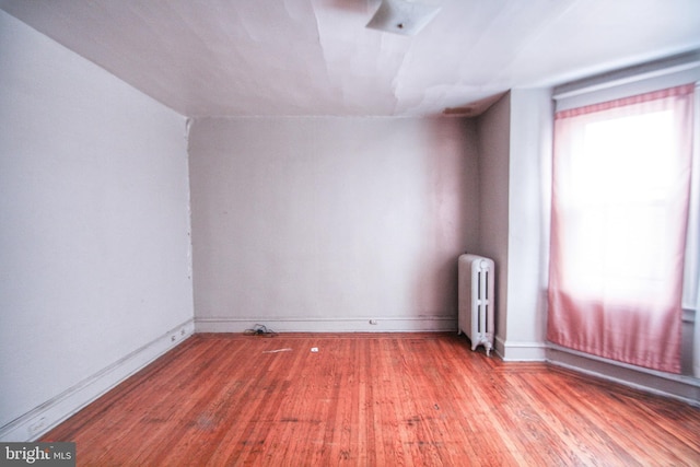 spare room featuring hardwood / wood-style flooring, lofted ceiling, and radiator heating unit