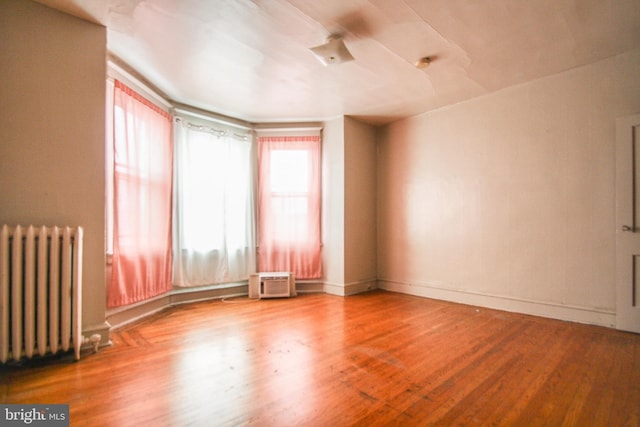 empty room with hardwood / wood-style flooring and radiator heating unit