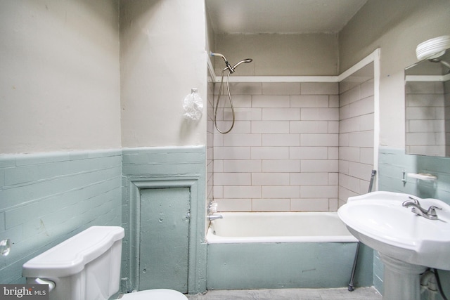 full bathroom featuring tiled shower / bath, toilet, tile walls, and sink