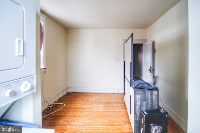 washroom with light wood-type flooring and stacked washer / dryer