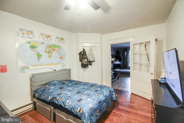 bedroom featuring baseboard heating, ceiling fan, a closet, and dark hardwood / wood-style floors