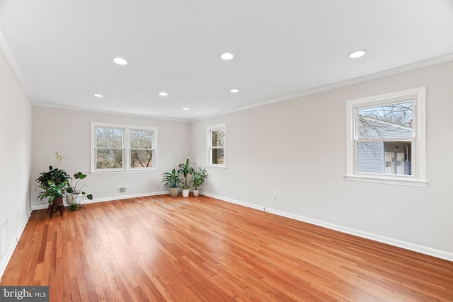 spare room featuring crown molding, plenty of natural light, and light wood-type flooring