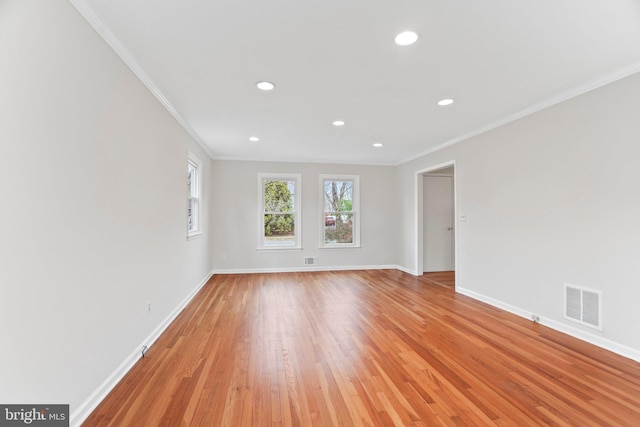 spare room with crown molding and light wood-type flooring