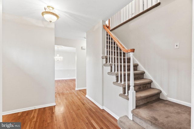 stairs featuring hardwood / wood-style flooring and a chandelier