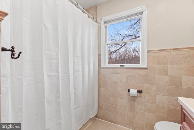 bathroom with tile walls, a shower with shower curtain, vanity, tile patterned floors, and toilet