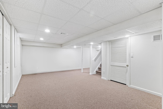 basement featuring a paneled ceiling and carpet flooring