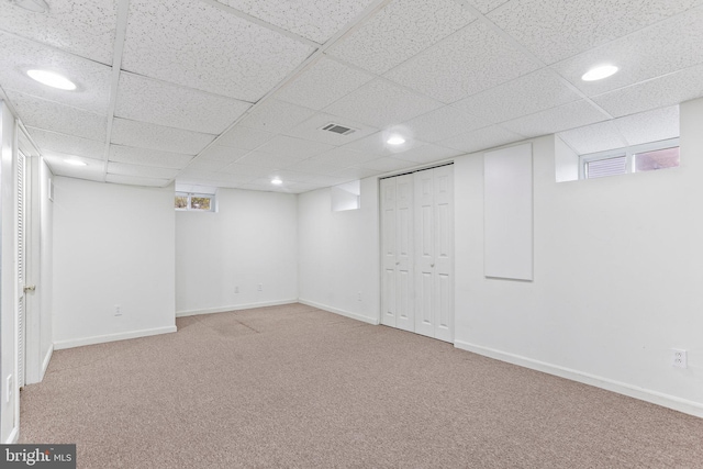 basement with a paneled ceiling and carpet flooring