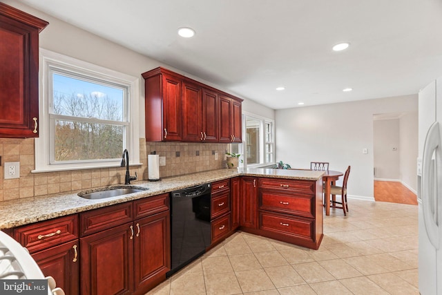 kitchen featuring light stone counters, sink, a wealth of natural light, and black dishwasher