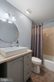 full bathroom with shower / bath combo with shower curtain, vanity, and toilet