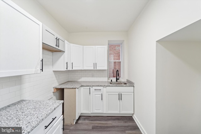 kitchen with white cabinetry, light stone countertops, sink, tasteful backsplash, and dark hardwood / wood-style flooring