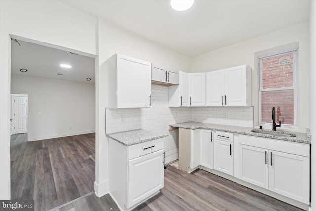 kitchen featuring white cabinets, wood-type flooring, sink, and tasteful backsplash