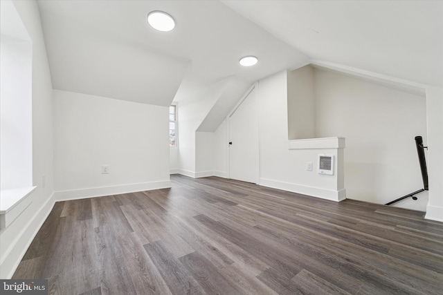 additional living space with heating unit, wood-type flooring, and vaulted ceiling