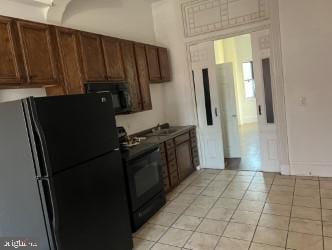 kitchen featuring sink, black appliances, and light tile patterned flooring