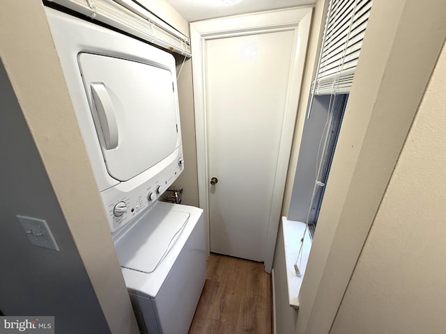 washroom with stacked washing maching and dryer and wood-type flooring