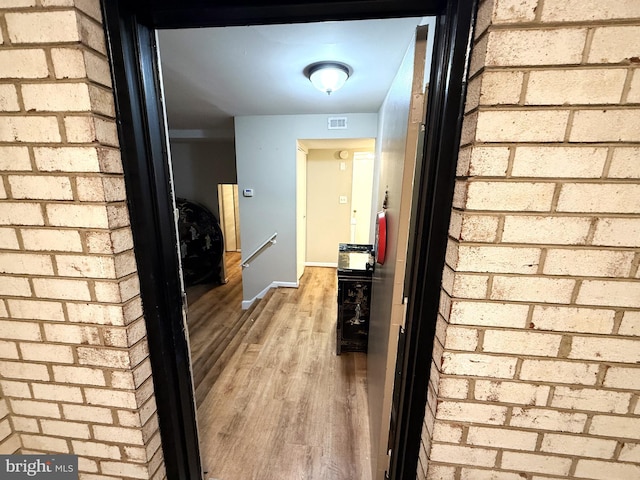 corridor featuring hardwood / wood-style floors and brick wall