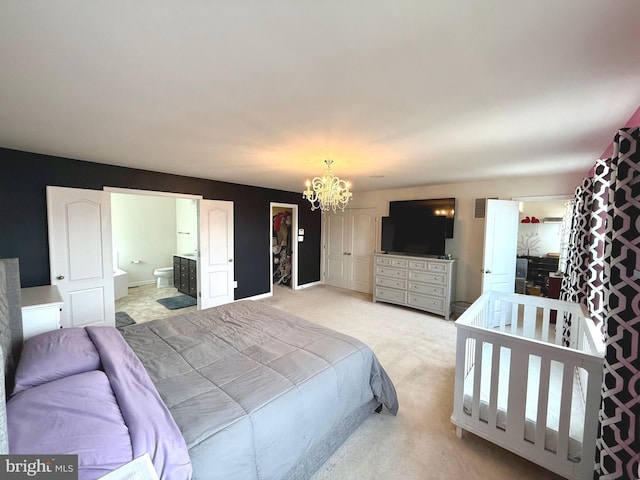 carpeted bedroom with connected bathroom and an inviting chandelier