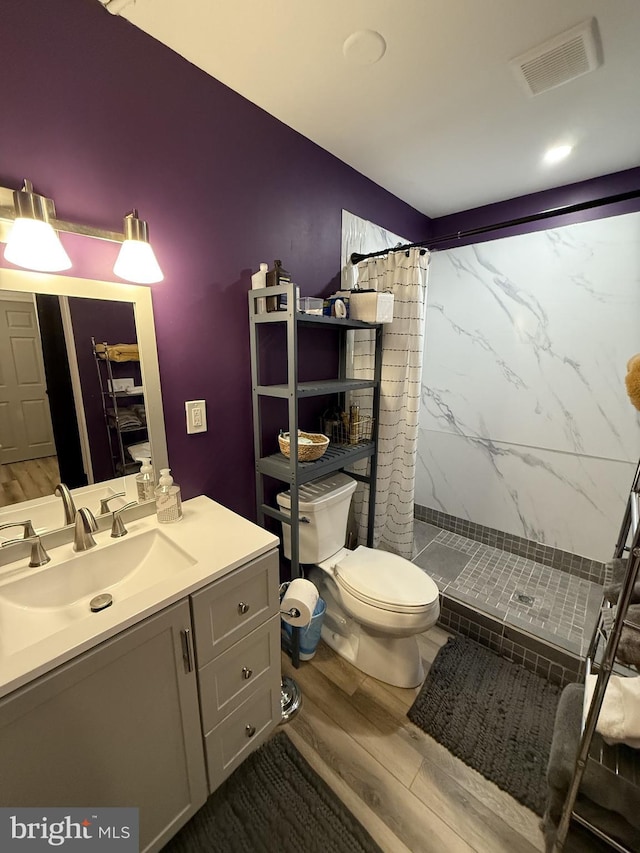 bathroom featuring a shower, wood-type flooring, vanity, and toilet