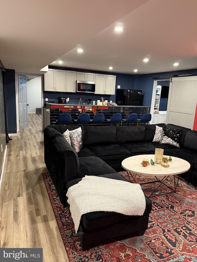 living room featuring a barn door and light hardwood / wood-style flooring