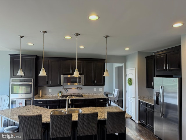 kitchen with pendant lighting, sink, a kitchen island with sink, and appliances with stainless steel finishes