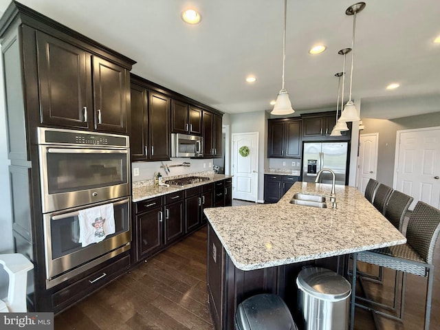 kitchen featuring a spacious island, sink, decorative light fixtures, a kitchen bar, and stainless steel appliances